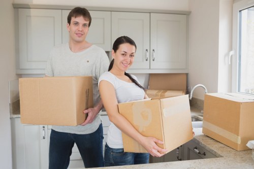 Professional movers carrying furniture through a narrow Shepherds Bush stairwell